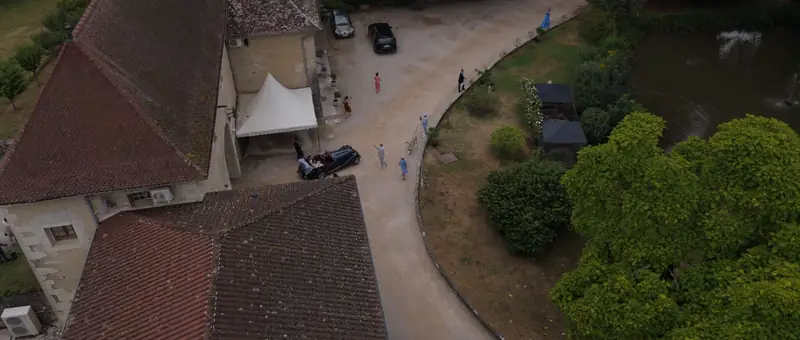 Vue aérienne de la cour du Château de Chapeau Cornu, avec ses toits de tuiles, sa tente blanche et l'étang