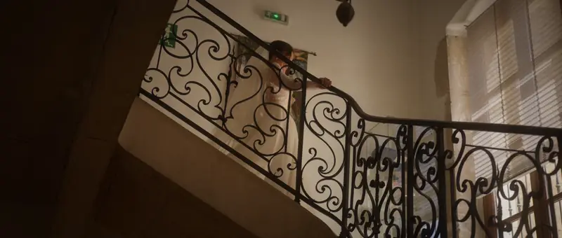 La mariée descend l'escalier à rampe en fer forgé du Château de Chapeau Cornu