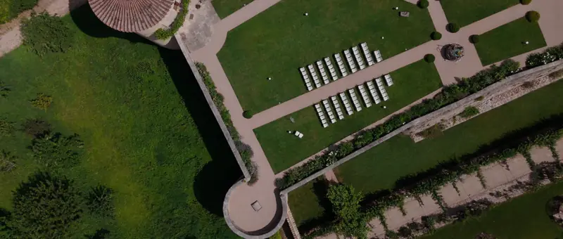 Vue aérienne des jardins du Château de Saint-Bernard, avec les chaises de la cérémonie installées sur la pelouse au pied des remparts