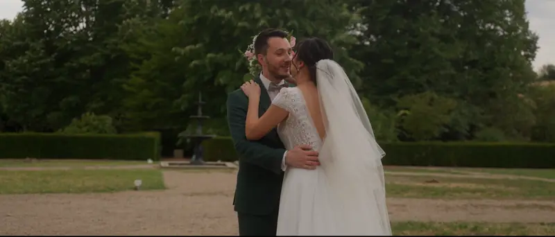 Les mariés enlacés dans le parc du Domaine de Grand Maison, devant la fontaine et les haies taillées