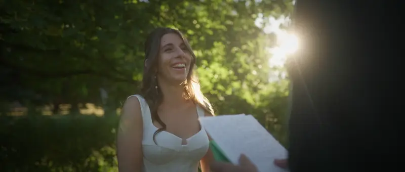 La mariée sourit en lisant ses vœux sous les arbres du Domaine de Tourieux