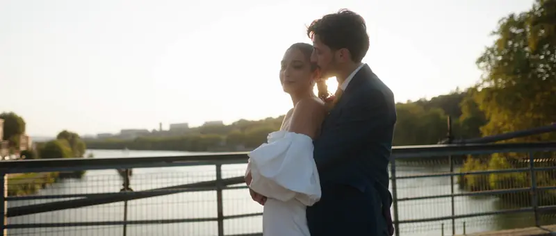 Les mariés enlacés sur une passerelle au bord de la Saône, à Lyon, au coucher du soleil