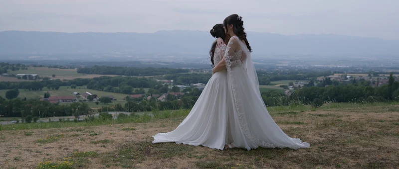Les deux mariées enlacées dans le pré de la Chartreuse de Pomier, face à la plaine et aux montagnes
