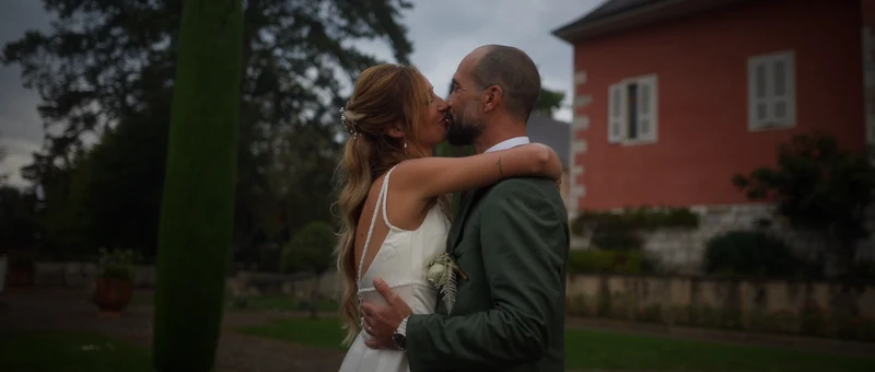Les mariés enlacés devant la façade rose du Château de Chitry