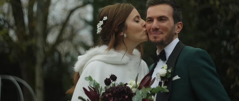 La mariée embrasse le marié sur la joue dans le jardin du Domaine des Saints Pères