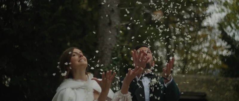 Les mariés sous une pluie de pétales blancs dans le jardin du Domaine des Saints Pères