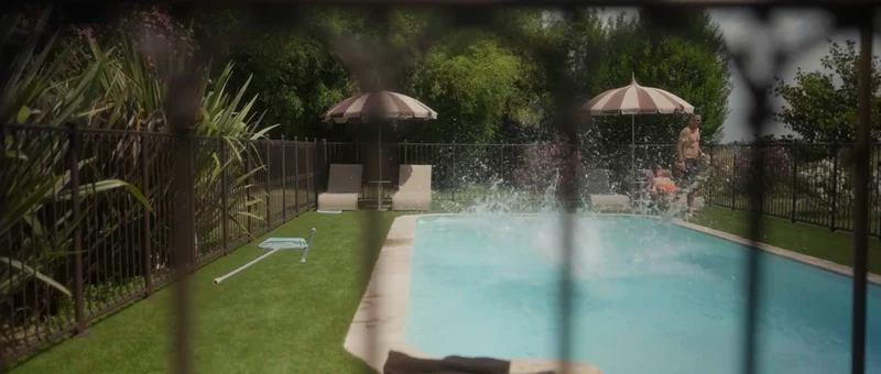 La piscine du Château Couffins, ses parasols rayés et son jardin