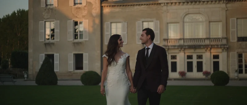 Les mariés main dans la main sur la pelouse, devant la façade du Château de Varennes, en fin de journée