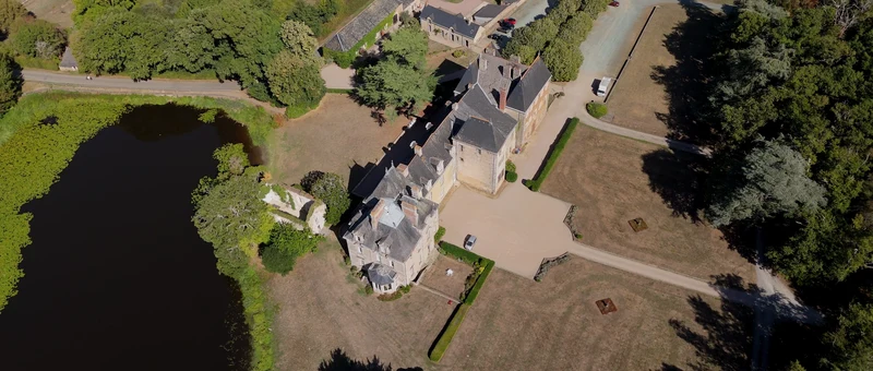 Le Château du Pordor, sa cour et son parc vus du drone, au bord de l'étang