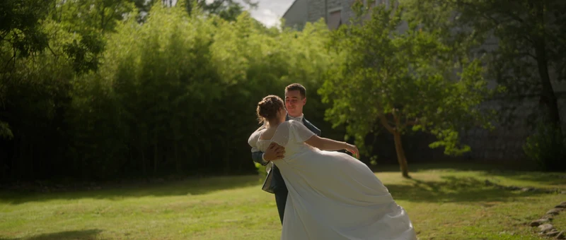 Le marié soulève la mariée sur la pelouse du parc du Château de Chaussy