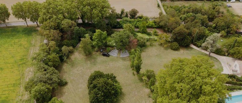 Le parc paysager du Domaine de Blacons vu du drone, entre les grands arbres et la piscine