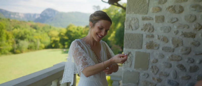 La mariée sur le balcon en pierre du Domaine de la Chartrognière, avec le Vercors en fond