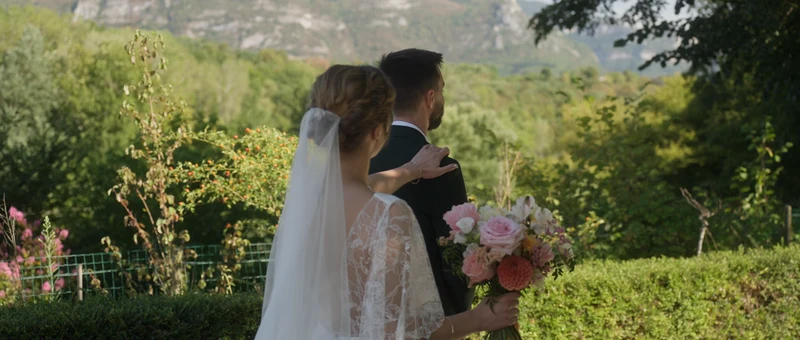 Les mariés de dos dans le jardin du Domaine de la Chartrognière, face aux falaises du Vercors