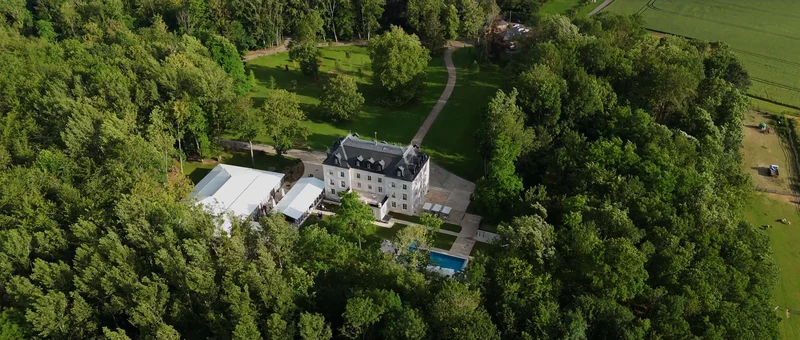 Le Château des Hauts de Provins vu du drone, avec son orangerie et sa piscine au milieu du parc boisé