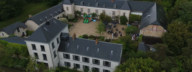 Le Domaine de Quincampoix vu du drone : la cour pavée et les bâtiments aux toits d'ardoise
