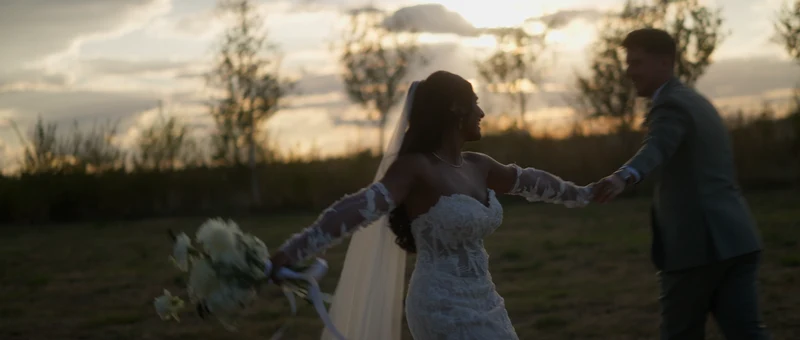 Les mariés dansent dans l'herbe haute du Domaine de Vaujoly, à la lumière du soir
