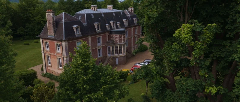 Le château du Domaine du Colombier vu du drone, entre les grands arbres du parc