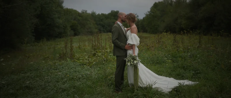Les mariés enlacés dans la prairie, à l'orée de la forêt du Manoir de Villefermoy