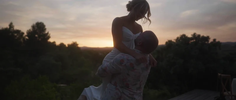 Le marié soulève la mariée au coucher du soleil, face aux collines d'Agel