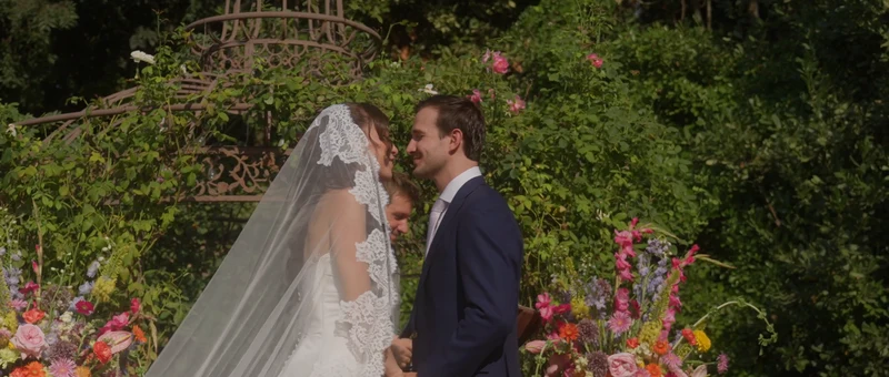 Les mariés sous la gloriette fleurie de la cérémonie, dans le jardin du Château de Paon