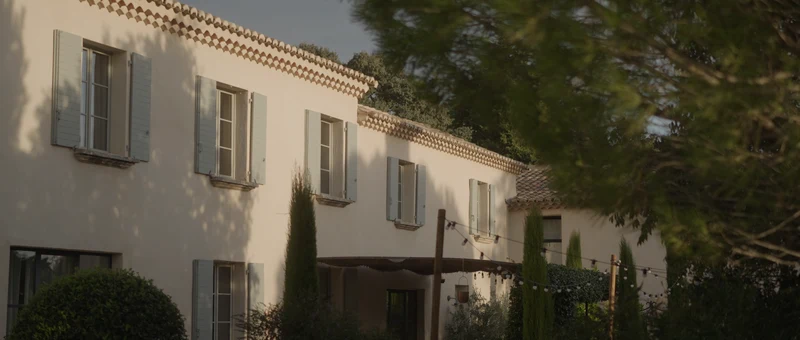 La façade du Mas des Costes, ses volets gris-bleu et ses cyprès, en fin de journée