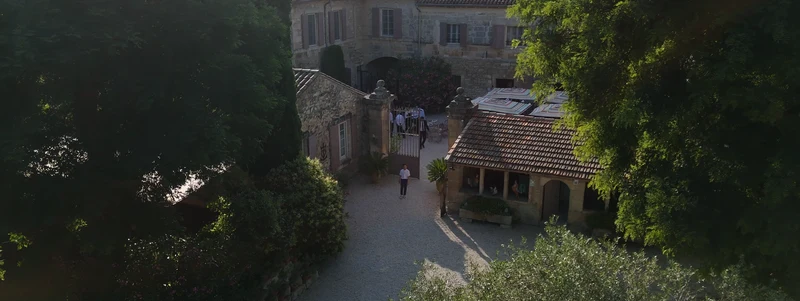 La cour et les bâtisses en pierre du Mas des Comtes de Provence, vues d'en haut entre les arbres