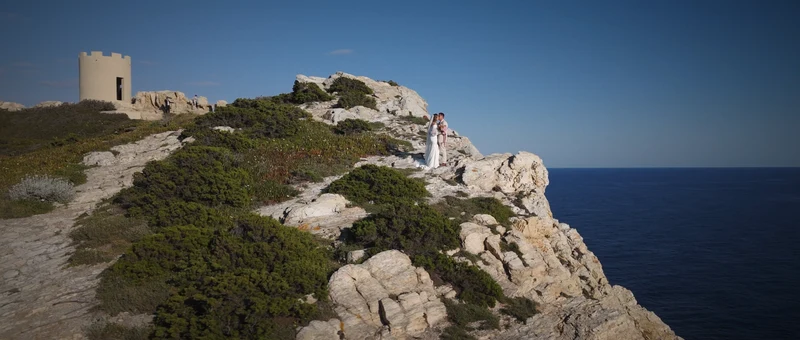 La falaise et la tour blanche de l'île des Embiez au-dessus de la mer, les mariés au loin sur les rochers