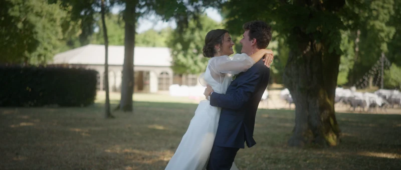 Le marié soulève la mariée dans le parc, devant l'orangerie du Château de La Grille